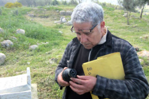 Lamri Chirouf inspects an Israeli tear gas canister in Budrus cemetery (Photo Credit: Amnesty International).