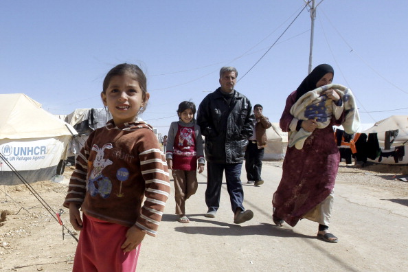 A Syrian family walk amid tents at the Za’atari refugee camp (Photo Credit: Khalil Mazraawi/AFP/Getty Images).