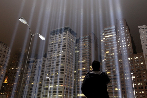 A worker looks up at beams of the Tribute in Lights ahead of the tenth anniversary of the September 11 attacks on September 7, 2011 in New York City. The Tribute in Light is comprised of 88,7000 watt searchlights that beam into the sky near the site of the World Trade Center in remembrance of the September 11 attacks (Photo Credit: Justin Sullivan/Getty Images).