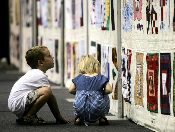 Chris Malone and his sister Samantha view sections of the 16,000 square foot United in Memory 9/11 Victims Memorial Quilt at George Washington University September 8, 2005 in Washington, D.C. (Photo Credit: Win McNamee via Getty Images).