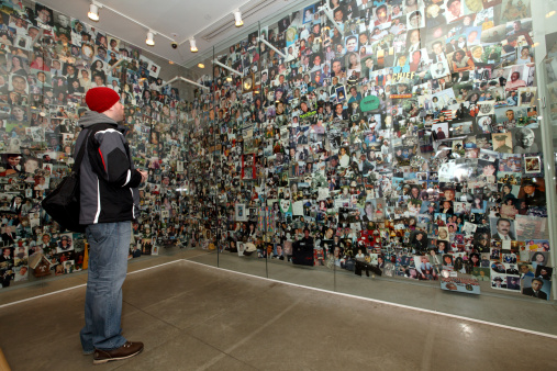 Man looking at pictures and personal items of September 11th victims at the Tribute WTC Visitor's Center, New York City (Photo Credit: Steven Greaves via Getty Images).