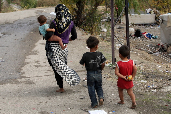 A Syrian refugee woman and children walk near their makeshift tents (Photo Credit: Adem Altan/AFP/Getty Images).