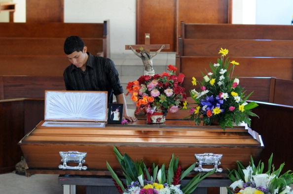 A young man stands beside the coffin of Honduran journalist Saira Fabiola Almendarez. According to the Honduran Human Right Defense Committee, 18 journalists have been murdered in the last three years in the country (Photo Credit: Orlando Sierra/AFP/Getty Images). 