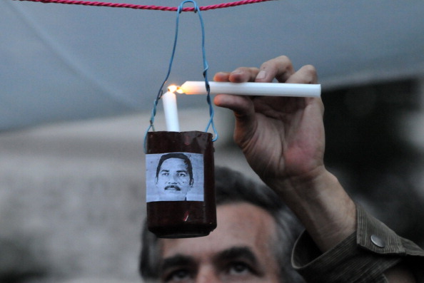 A man lights a candle during a vigil in memory of over 20 journalists killed in Honduras in the last three years (Photo Credit: Orlando Sierra/AFP/Getty Images).