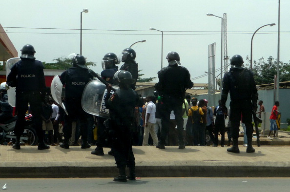 Angolan riot policemen stand in front of hundreds of demonstrators protesting against the killings of two young opposition activists in Luanda (Photo Credit: Estelle Maussion/AFP/Getty Images).
