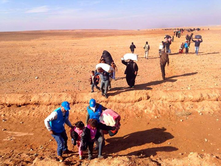 Syrian women, men and children, crossing the border to Jordan. Forced to leave everything behind, except what they can carry, they're running for their lives (Photo Credit: Sweaters for Syria).