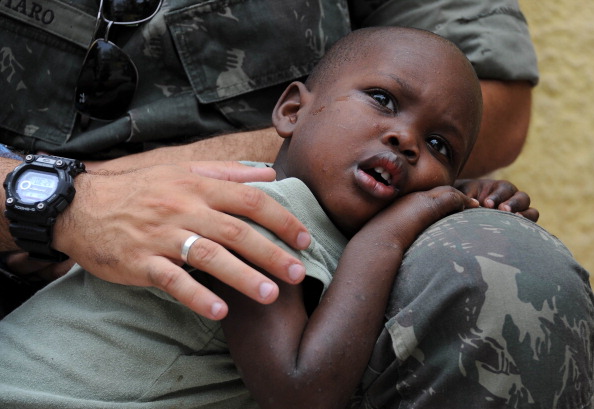 A Brazilian soldier of the MINUSTAH force hugs an Haitian child orphaned by the 2010 earthquake (Photo Credit: Vanderlei Almeida/AFP/Getty Images).