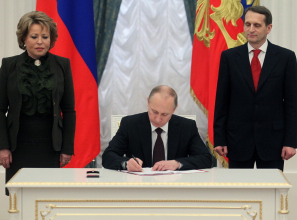 Russian President Vladimir Putin signing the final decree completing annexation of Crimea on March 21, 2014 in Moscow (Photo Credit: Sasha Mordovets/Getty Images).