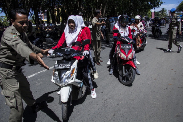 Aceh’s Shari’a laws targeting women have made news a number of times, including this spring when police pulled women over and forcing them to sit sideways on motorbikes, with their legs dangling by the rear wheel (Photo credit should read REZA JUANDA/AFP/Getty Images).