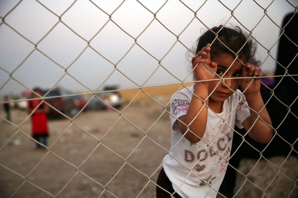 An Iraqi child waits with her family outside of a temporary displacement camp for Iraqis caught-up in the fighting in Khazair, Iraq. Khazair is now home to an estimated 1,500 internally displaced persons (IDP's) with the number rising daily (Photo Credit: Spencer Platt/Getty Images).