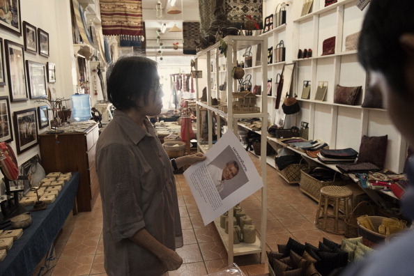 Sombath Somphone's wife, Ng Shui Meng, handles a 'missing person' poster of her husband at Saoban, a store selling Lao Village handicrafts that she established with her husband. (Photo credit: Gilles Sabrie/LightRocket via Getty Images)
