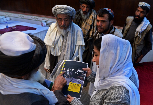Afghan relatives of civilian victims of the country's conflict examine the Amnesty International report detailing those killed by U.S. forces in the country at a press conference in Kabul on August 11, 2014. The families of thousands of civilians killed by American forces in Afghanistan have been left without justice or compensation. (Photo credit: Wakil Kohsar/AFP/Getty Images)