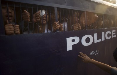 Student protesters try to speak to their family members from a prison vehicle as they are transported to a court in Letpadan on March 11, 2015. Anxious families of scores of arrested Myanmar activists on March 11 sought news of relatives detained by police in a violent student protest crackdown, which sparked international condemnation and fears of a return to junta-era repression. AFP PHOTO / Ye Aung THU        (Photo credit should read Ye Aung Thu/AFP/Getty Images)