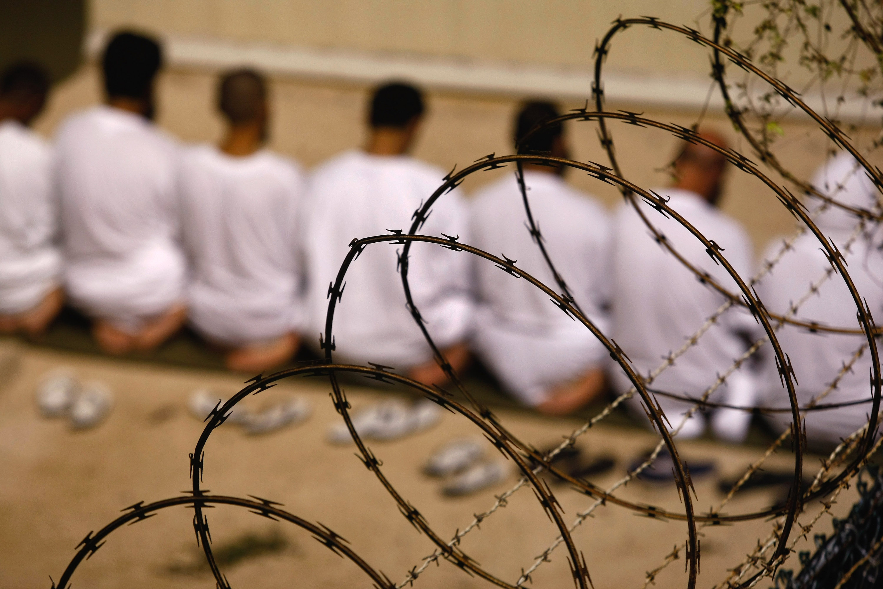 GUANTANAMO BAY, CUBA - OCTOBER 28: (EDITORS NOTE: Image has been reviewed by U.S. Military prior to transmission)  A group of detainees kneels during an early morning Islamic prayer in their camp at the U.S. military prison for &quot;enemy combatants&quot; on October 28, 2009 in Guantanamo Bay, Cuba. Although U.S. President Barack Obama pledged in his first executive order last January to close the infamous prison within a year's time, the government has been struggling to try the accused terrorists and to transfer them out ahead of the deadline. Military officials at the prison point to improved living standards and state of the art medical treatment available to detainees, but the facility's international reputation remains tied to the &quot;enhanced interrogation techniques&quot; such as waterboarding employed under the Bush administration. (Photo by John Moore/Getty Images)