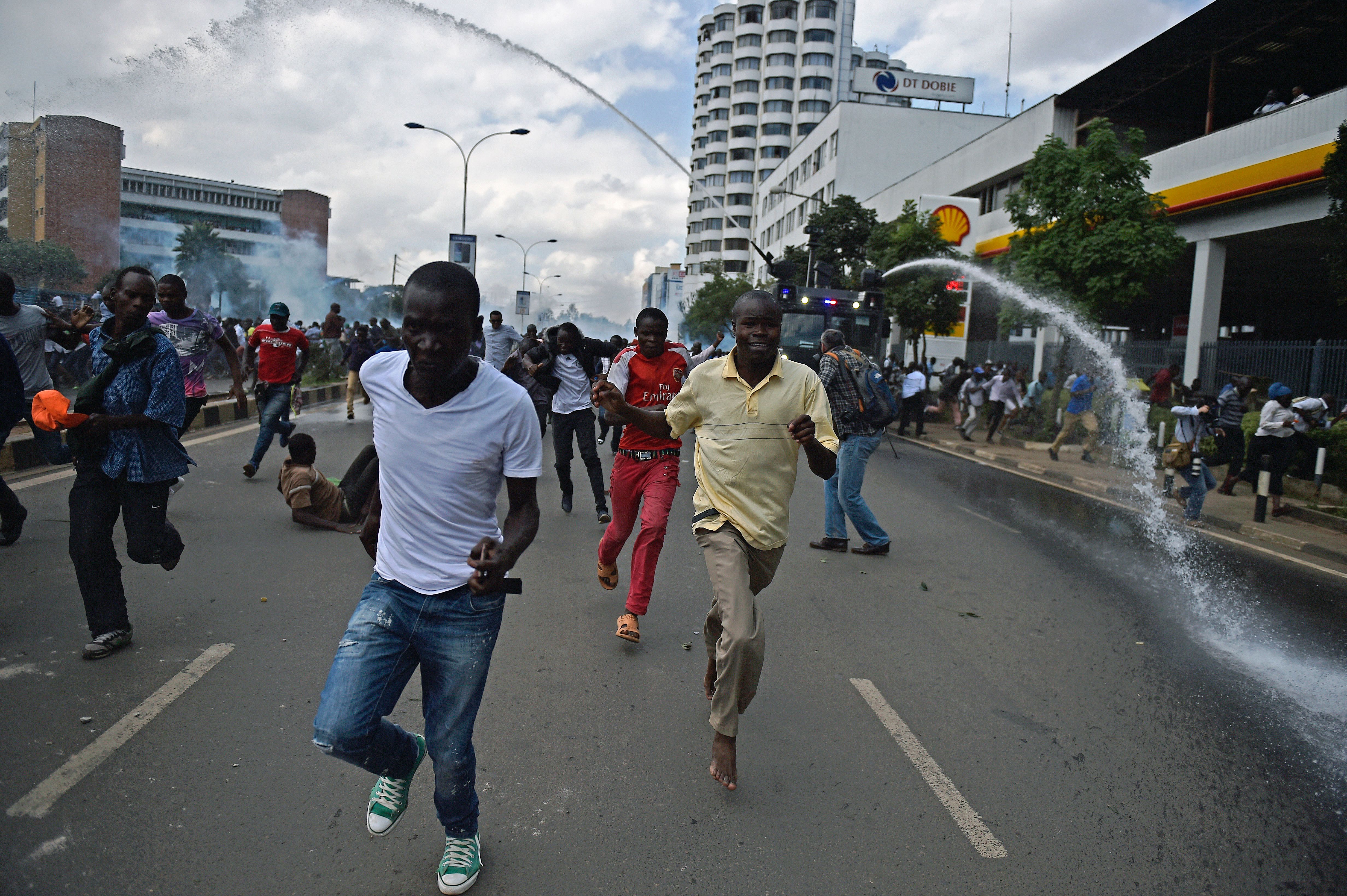 TOPSHOT - Protestors run from water canons after Kenya's opposition supporters demonstrated in Nairobi, on May 16, 2016. Opposition protestors led by former Prime Minister Raila Odinga had gathered outside the Indepedent Electoral and Boundaries Comission building to demand the dismissal of IEBC commissioners from office citing alleged bias towards the ruling Jubillee Alliance Party. / AFP / CARL DE SOUZA        (Photo credit should read CARL DE SOUZA/AFP/Getty Images)