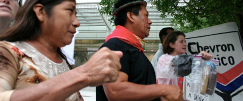 Emergildo Criollo, a leader from the Cofan tribe in Ecuador and Rita Maldonado, a Guanta community member at the demonstration outside the Chevron shareholder meeting. Behind them, an activist holds bottles of contaminated water. Photo: Amazon Watch