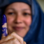 An Afghan voter shows her inked finger after she cast her ballot at a local polling station (Photo Credit: Shah Marai/AFP/Getty Images).