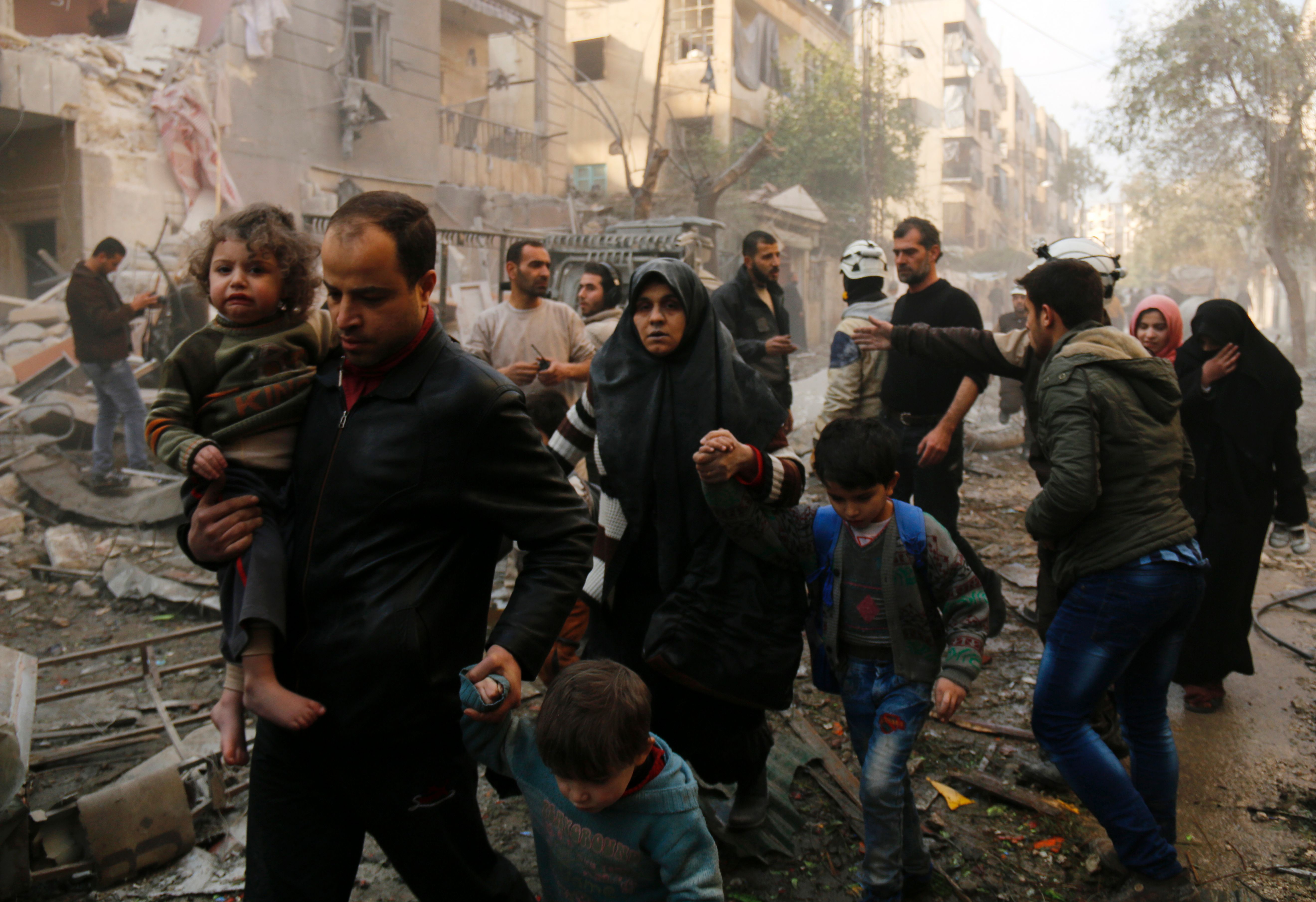 TOPSHOT - Syrians make their way through debris as they leave for a safer place following air strikes in the rebel-controlled side of the northern city of Aleppo on January 13, 2016. On January 12, 2016, suspected Russian strikes killed 57 civilians, including children and paramedics, in Idlib province, adjacent to Latakia, and in Aleppo, Syrian Observatory for Human Rights said. / AFP / KARAM AL-MASRI        (Photo credit should read KARAM AL-MASRI/AFP/Getty Images)